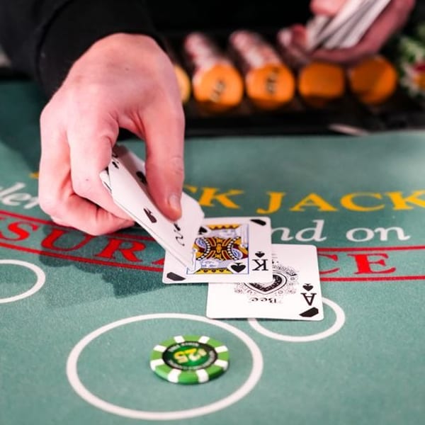 A dealer's hands revealing playing cards on a green blackjack table with chips.