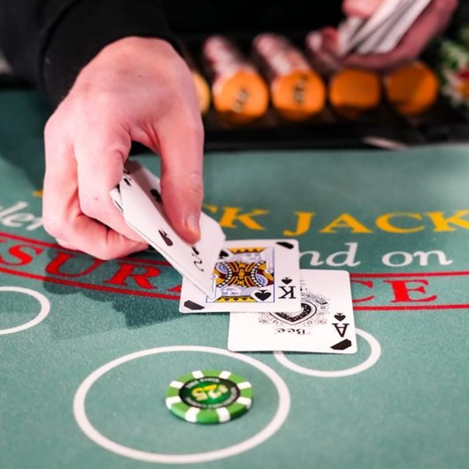 A dealer's hands revealing playing cards on a green blackjack table with chips.