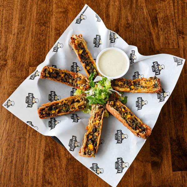 Six crispy pastry rolls filled with vegetables, served with a side of ranch and lettuce.