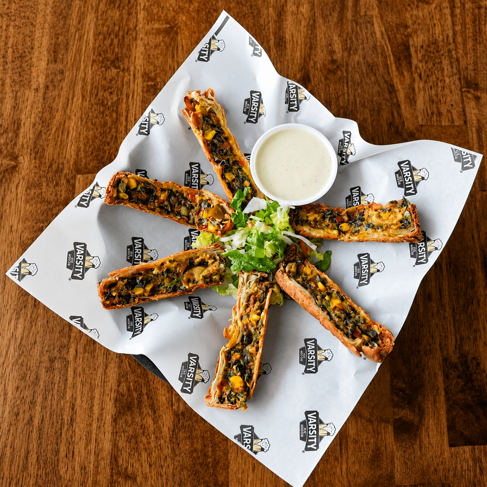 Six crispy pastry rolls filled with vegetables, served with a side of ranch and lettuce.